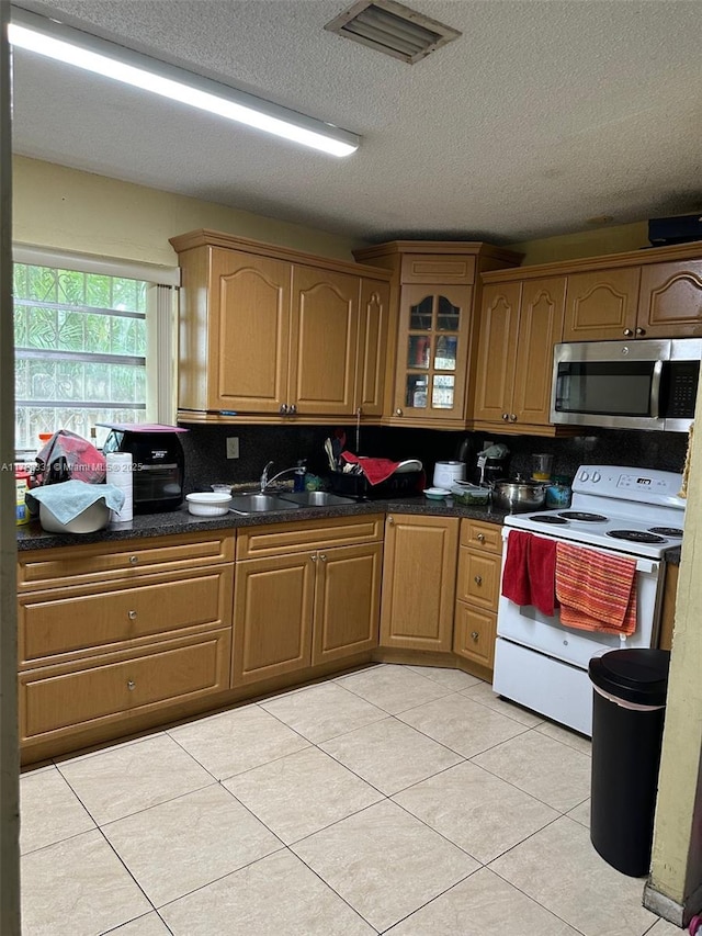 kitchen featuring dark stone countertops, electric range, sink, a textured ceiling, and light tile patterned floors