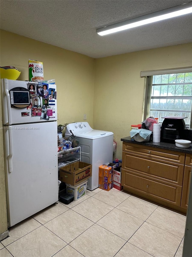 washroom with washer / clothes dryer, light tile patterned flooring, and a textured ceiling