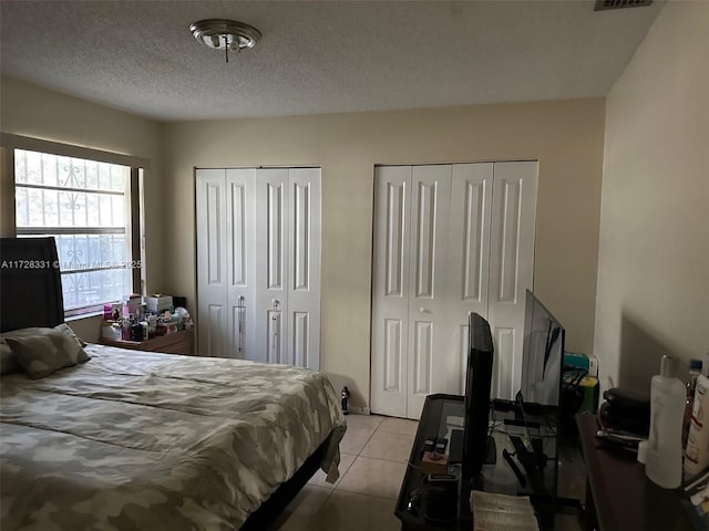 tiled bedroom with a textured ceiling and two closets