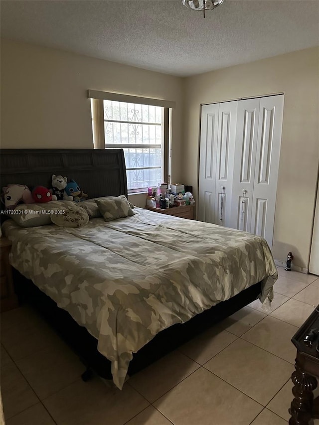 bedroom featuring a textured ceiling, a closet, and light tile patterned flooring