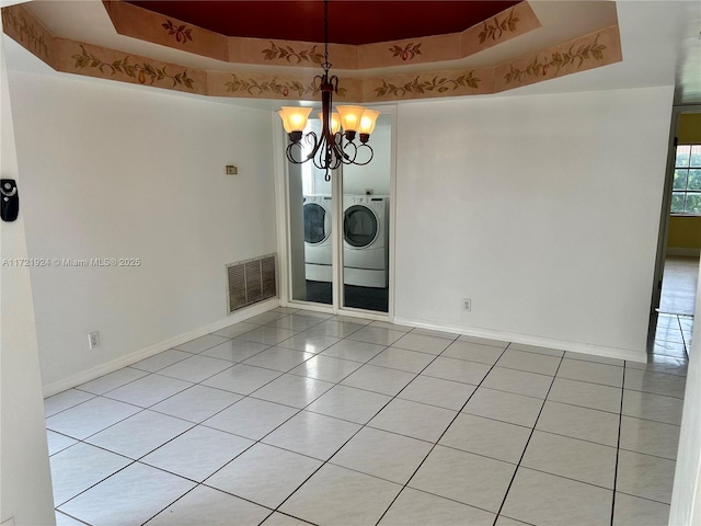 interior space with a raised ceiling, washer and clothes dryer, and a notable chandelier