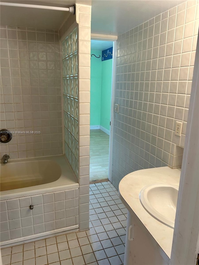 bathroom with tile patterned flooring, tiled shower / bath combo, tile walls, and vanity