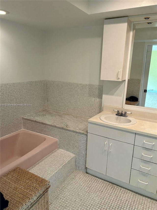 bathroom with a bathing tub, tile walls, tile patterned floors, and vanity