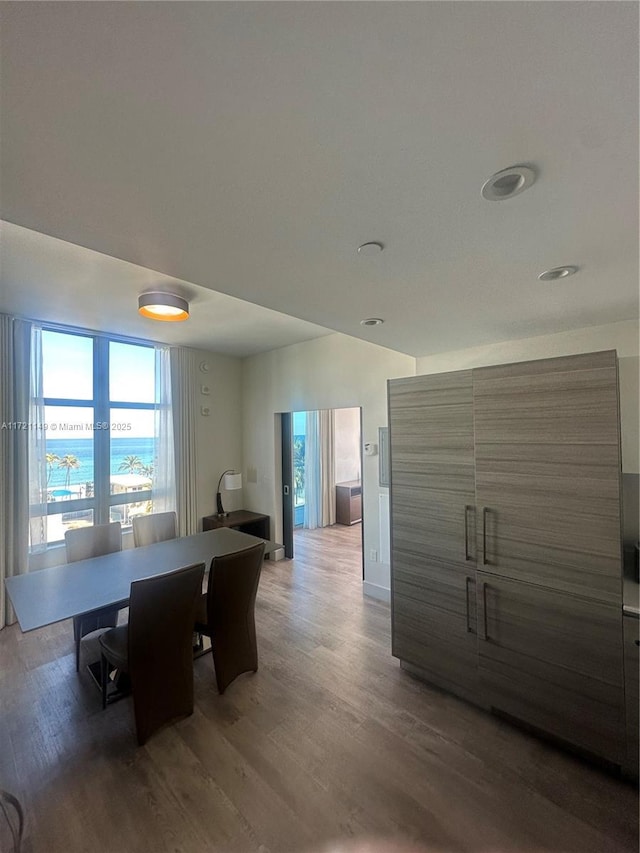 dining area with dark wood-type flooring and a water view