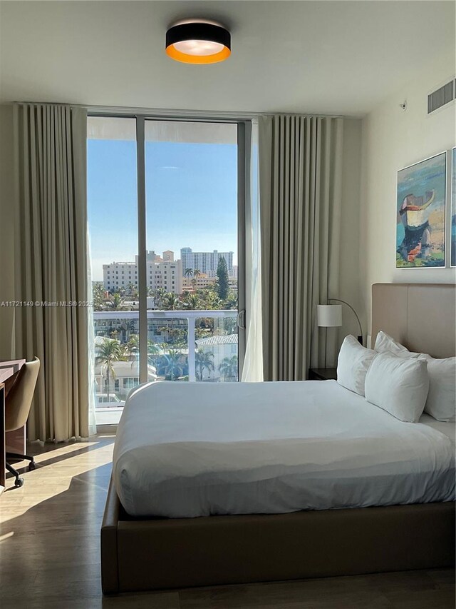 bedroom with expansive windows and wood-type flooring