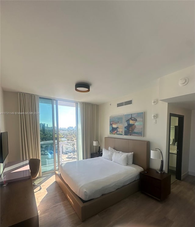 bedroom with access to exterior, a wall of windows, and dark hardwood / wood-style flooring