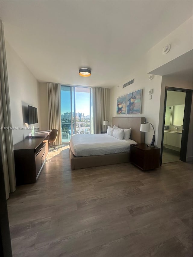 bedroom with ensuite bath, dark hardwood / wood-style flooring, and floor to ceiling windows