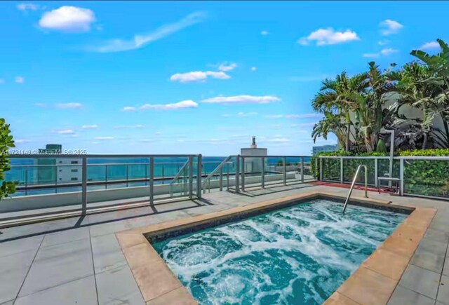 view of swimming pool featuring a water view and an in ground hot tub