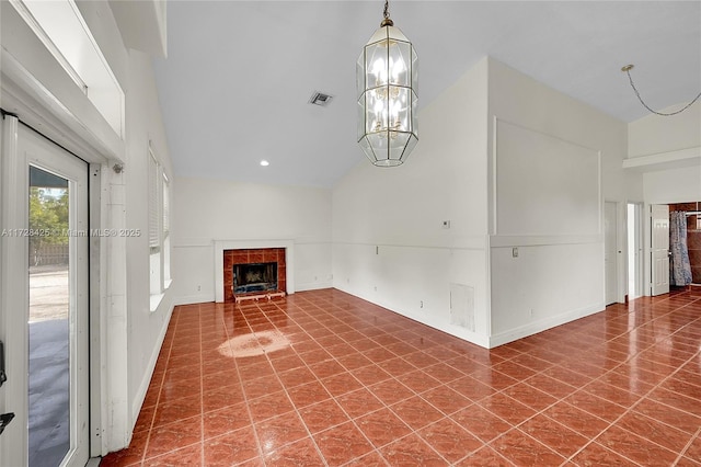 unfurnished living room with tile patterned flooring, a tile fireplace, a chandelier, and vaulted ceiling