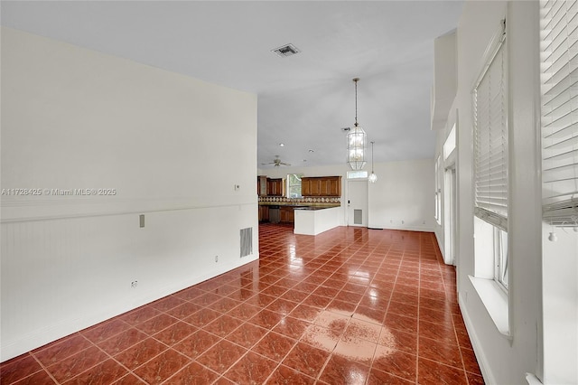 unfurnished living room featuring ceiling fan and dark tile patterned flooring