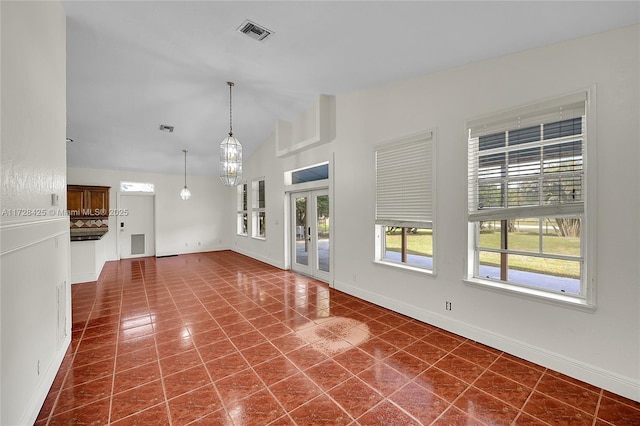 tiled spare room featuring lofted ceiling and french doors