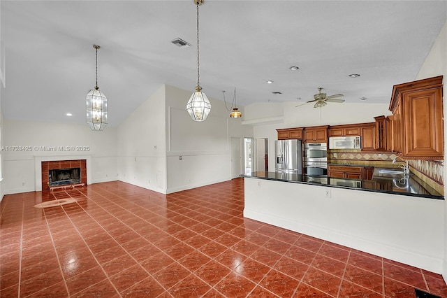 kitchen with appliances with stainless steel finishes, decorative backsplash, sink, hanging light fixtures, and ceiling fan