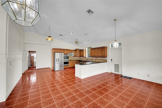 kitchen with ceiling fan, dark tile patterned flooring, kitchen peninsula, hanging light fixtures, and stainless steel appliances