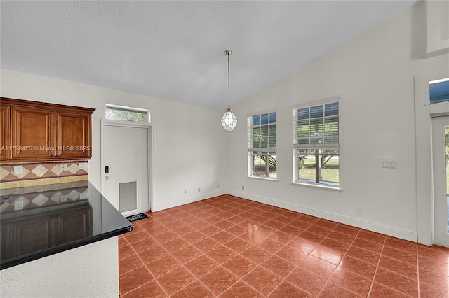 unfurnished dining area with vaulted ceiling and tile patterned flooring