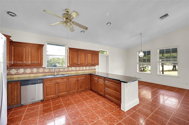 kitchen featuring dark tile patterned flooring, dishwasher, lofted ceiling, decorative backsplash, and sink