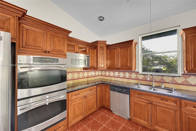 kitchen with stainless steel appliances, decorative backsplash, lofted ceiling, pendant lighting, and sink