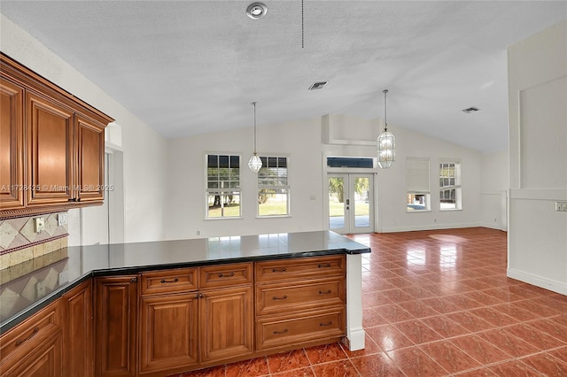 kitchen with a textured ceiling, tile patterned floors, french doors, vaulted ceiling, and pendant lighting