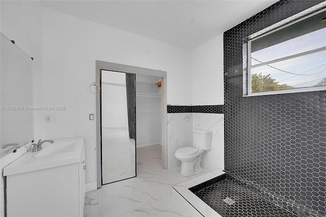 bathroom featuring toilet, a shower, tile walls, and vanity