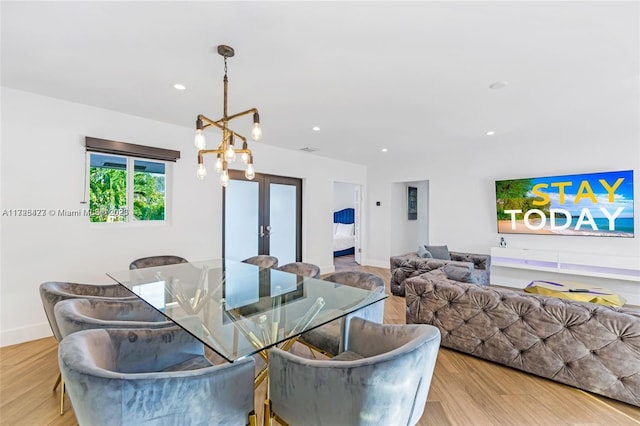 dining area with french doors, an inviting chandelier, and light hardwood / wood-style floors