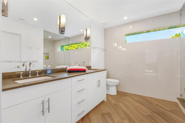 bathroom featuring toilet, vanity, walk in shower, and hardwood / wood-style flooring