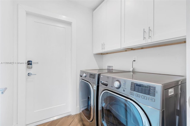 clothes washing area with washing machine and dryer, cabinets, and light hardwood / wood-style floors