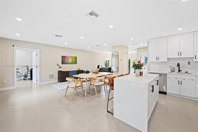 kitchen featuring white cabinets, dishwasher, sink, and a kitchen island