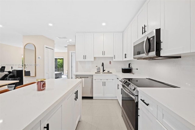 kitchen featuring white cabinets, appliances with stainless steel finishes, sink, and light tile patterned floors