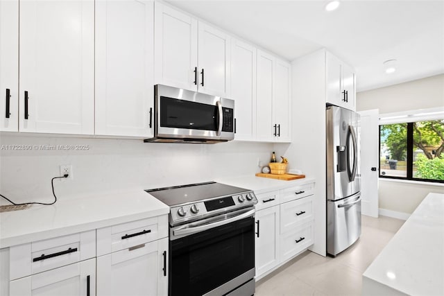 kitchen featuring light tile patterned flooring, appliances with stainless steel finishes, and white cabinetry