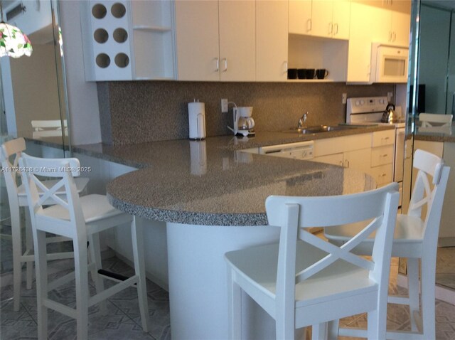 kitchen featuring tile patterned flooring, white cabinetry, tasteful backsplash, sink, and kitchen peninsula