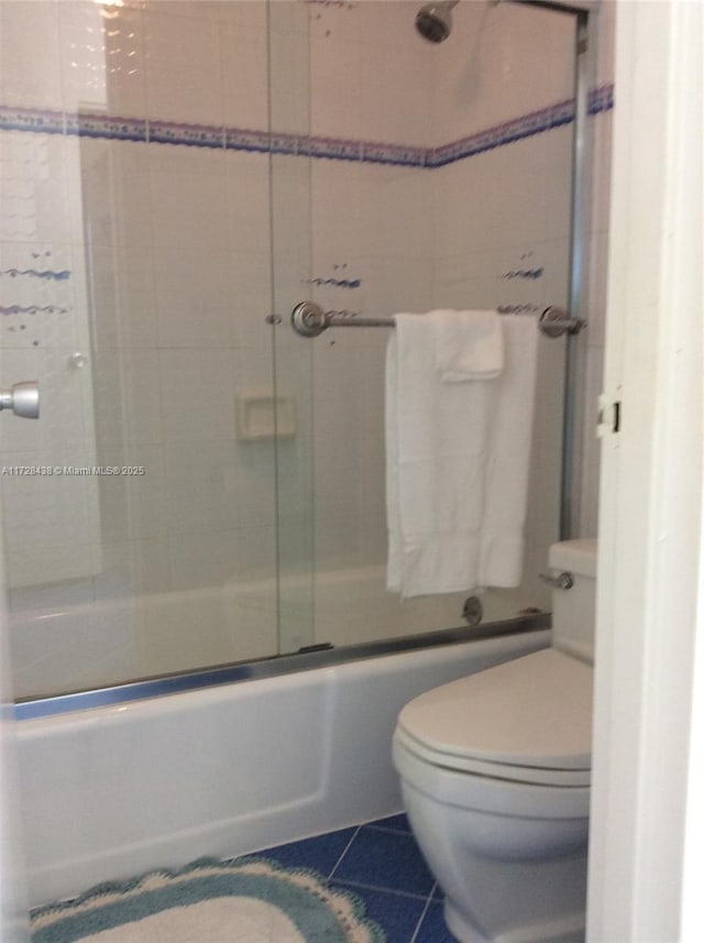 bathroom featuring bath / shower combo with glass door, tile patterned floors, and toilet