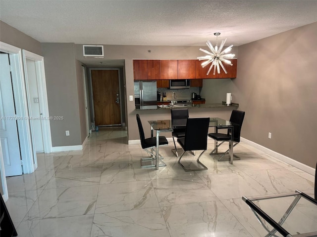 kitchen with pendant lighting, kitchen peninsula, a kitchen bar, an inviting chandelier, and appliances with stainless steel finishes