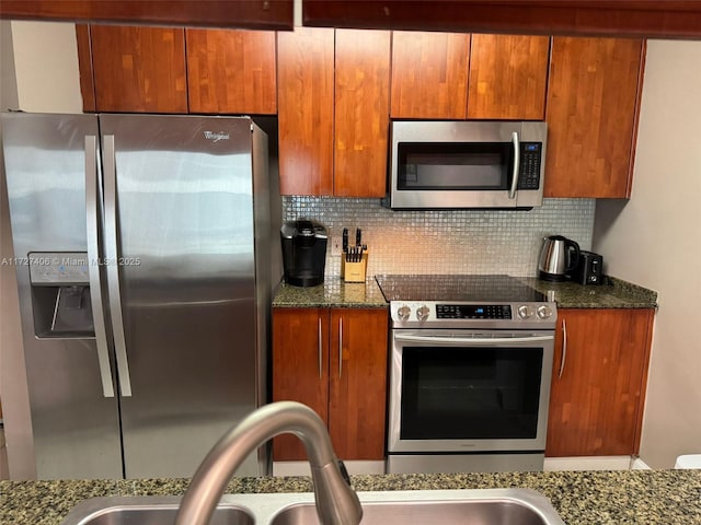 kitchen with tasteful backsplash, appliances with stainless steel finishes, and dark stone countertops