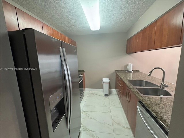 kitchen featuring sink, a textured ceiling, stainless steel appliances, and dark stone countertops