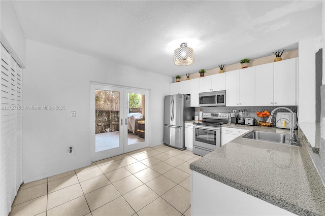 kitchen featuring sink, appliances with stainless steel finishes, white cabinetry, backsplash, and french doors