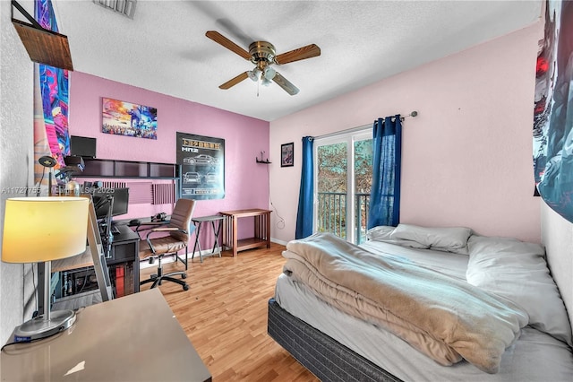 bedroom featuring hardwood / wood-style flooring, access to exterior, a textured ceiling, and ceiling fan