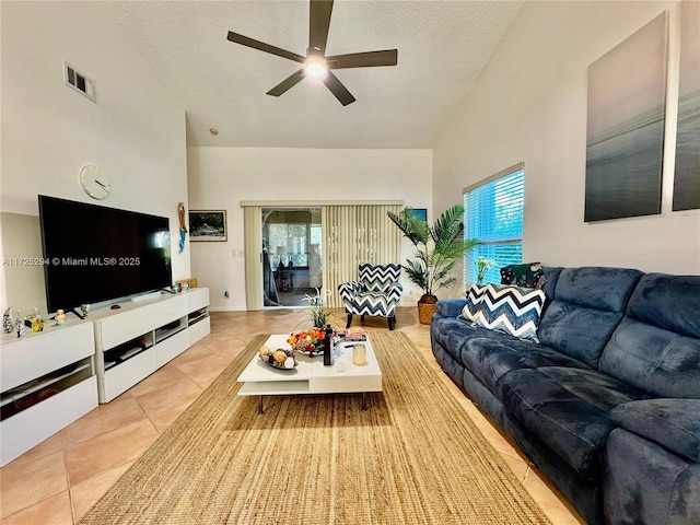 tiled living room featuring ceiling fan, a textured ceiling, and a healthy amount of sunlight