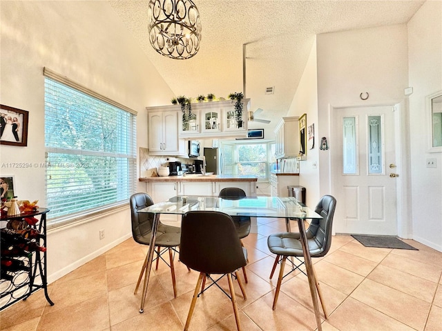 dining room featuring high vaulted ceiling, a notable chandelier, light tile patterned flooring, and a textured ceiling