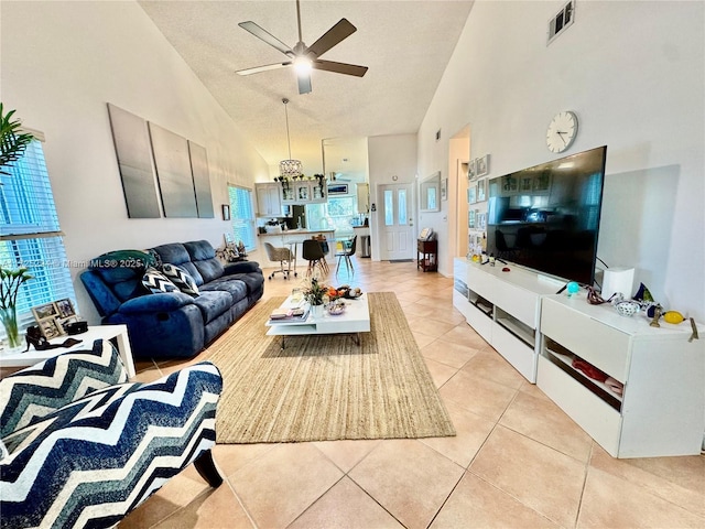 tiled living room with a textured ceiling, ceiling fan, and high vaulted ceiling