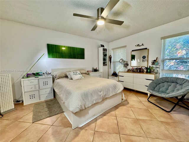 bedroom with ceiling fan, light tile patterned flooring, and a textured ceiling