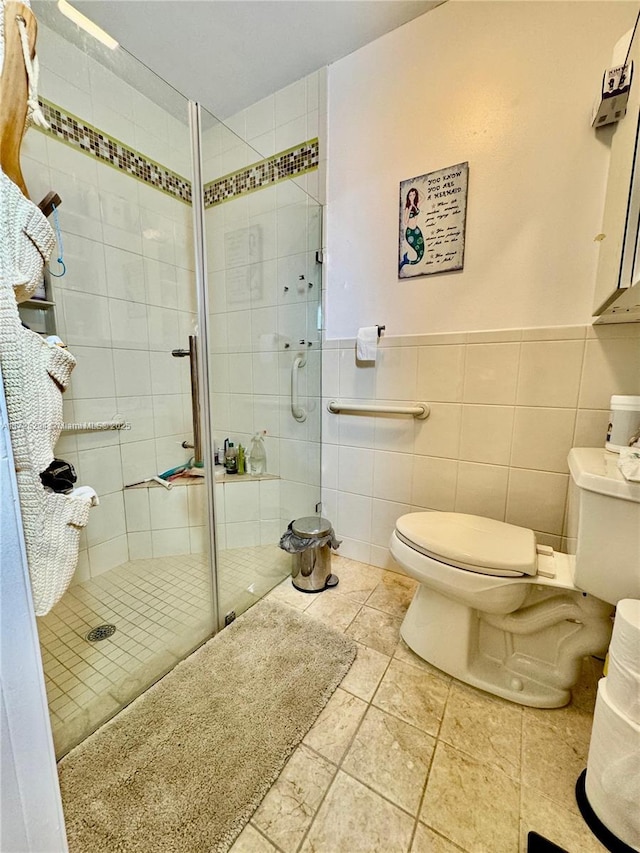 bathroom featuring toilet, tile walls, and a shower with shower door