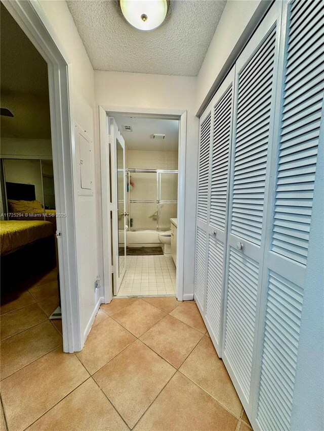 corridor featuring a textured ceiling and light tile patterned floors