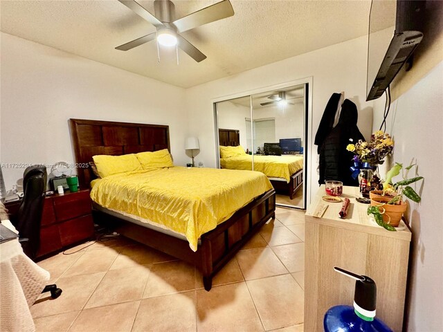 tiled bedroom with ceiling fan, a textured ceiling, and a closet