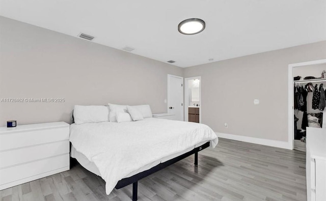 bedroom featuring ensuite bath, wood-type flooring, a closet, and a walk in closet