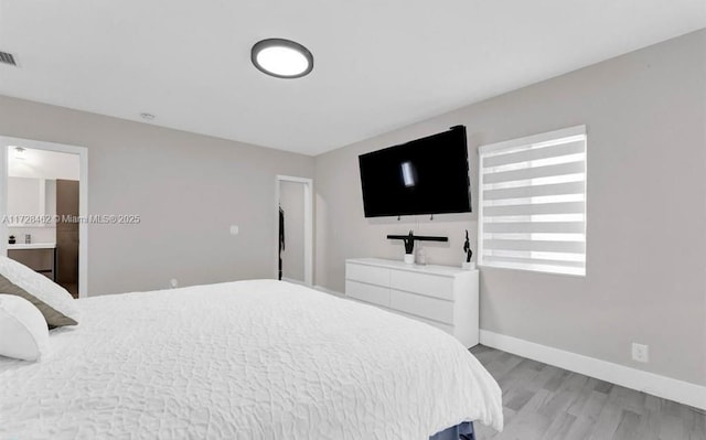 bedroom featuring connected bathroom and light hardwood / wood-style flooring