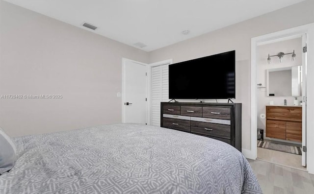 bedroom featuring connected bathroom and light hardwood / wood-style floors