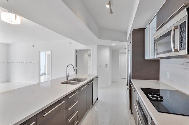 kitchen featuring dark brown cabinetry, stainless steel appliances, sink, rail lighting, and light tile patterned floors