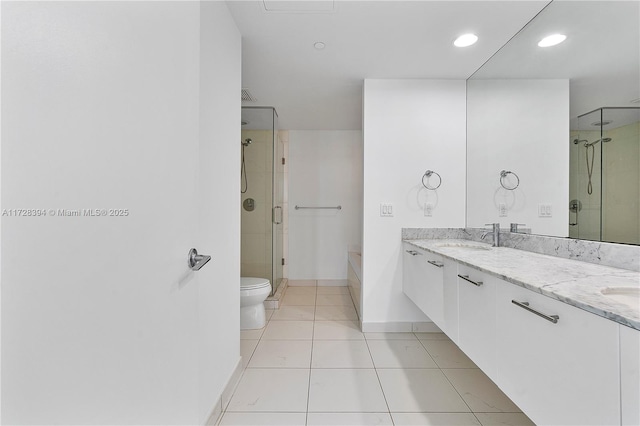 bathroom featuring toilet, vanity, tile patterned floors, and a shower with shower door