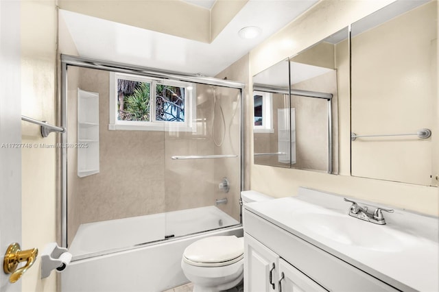 full bathroom featuring combined bath / shower with glass door, vanity, and toilet