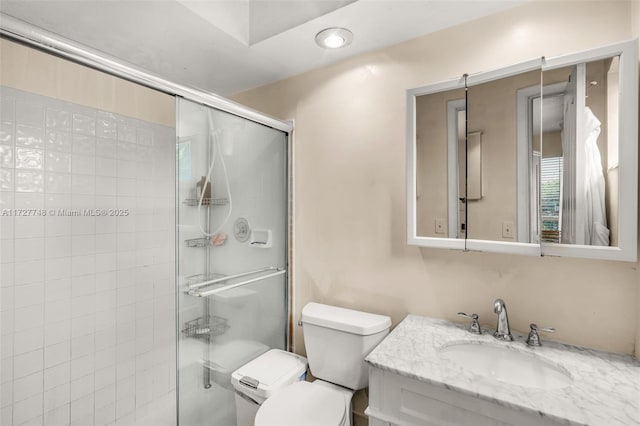 bathroom with an enclosed shower, vanity, and toilet