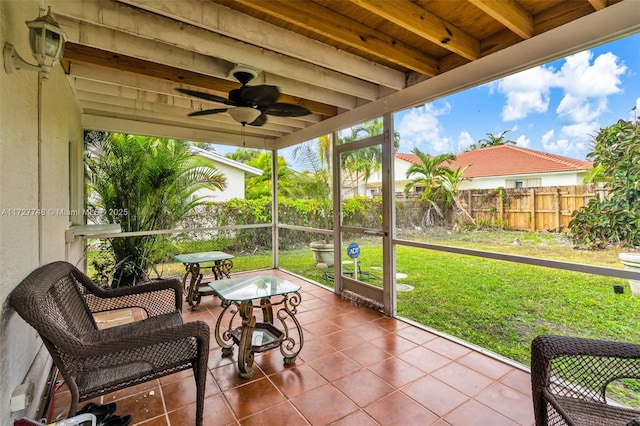 sunroom with ceiling fan and beam ceiling